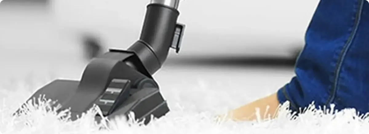 Close-up of a professional vacuuming a white carpet in Arabi.