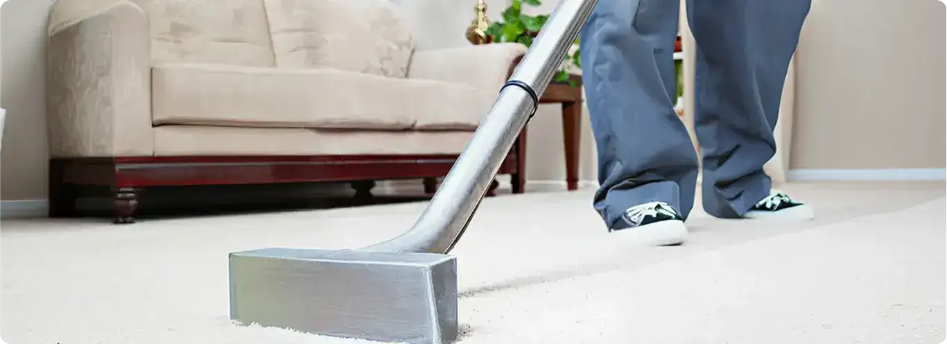 Carpet cleaning technician using a hot-water extraction wand on a light-colored carpet in a living room, New Orleans, LA.