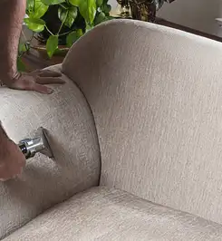 Professional upholstery cleaner deep-cleaning a fabric sofa with a handheld extraction tool and hose New Orleans, LA.